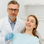 Odontólogo sonriente junto a paciente joven en consulta dental moderna